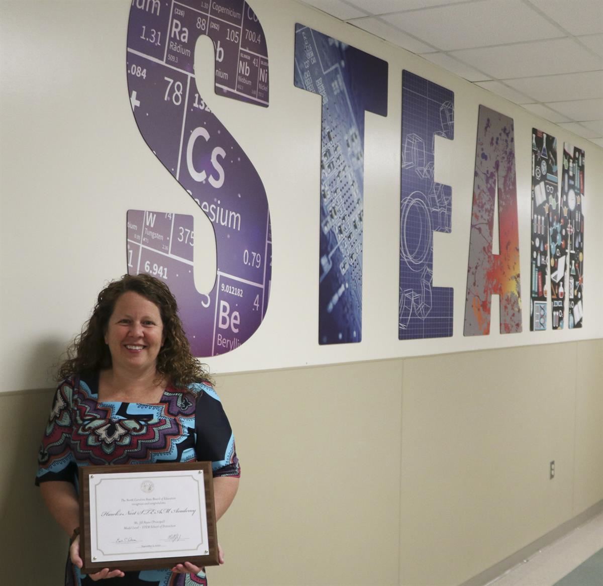 Dr. Jill Payne, principal of Hawks Nest STEAM Academy, shows off the North Carolina STEM School of Distinction award. 